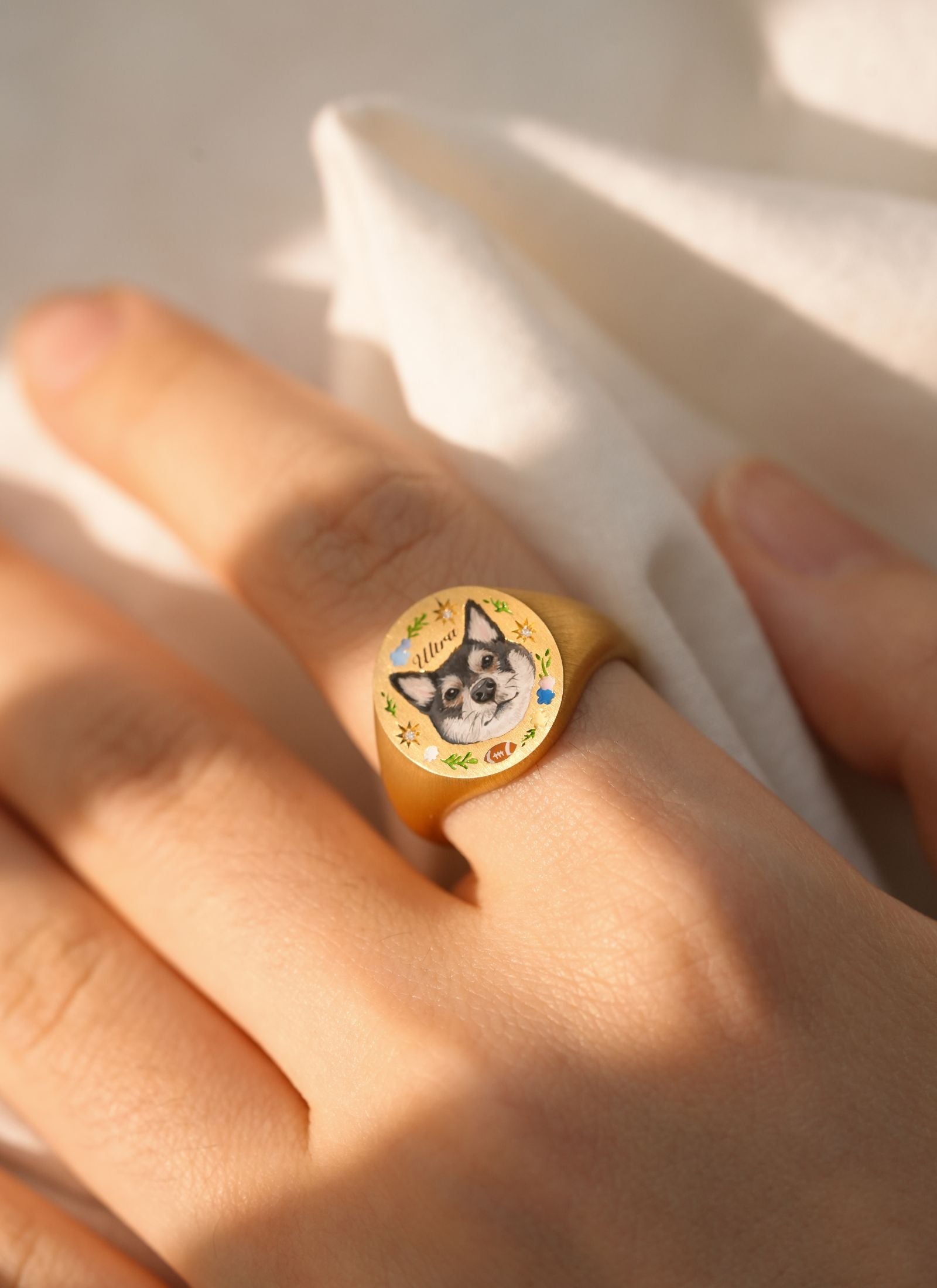Close-up of a hand wearing a dog portrait memorial ring, custom painted for pet remembrance