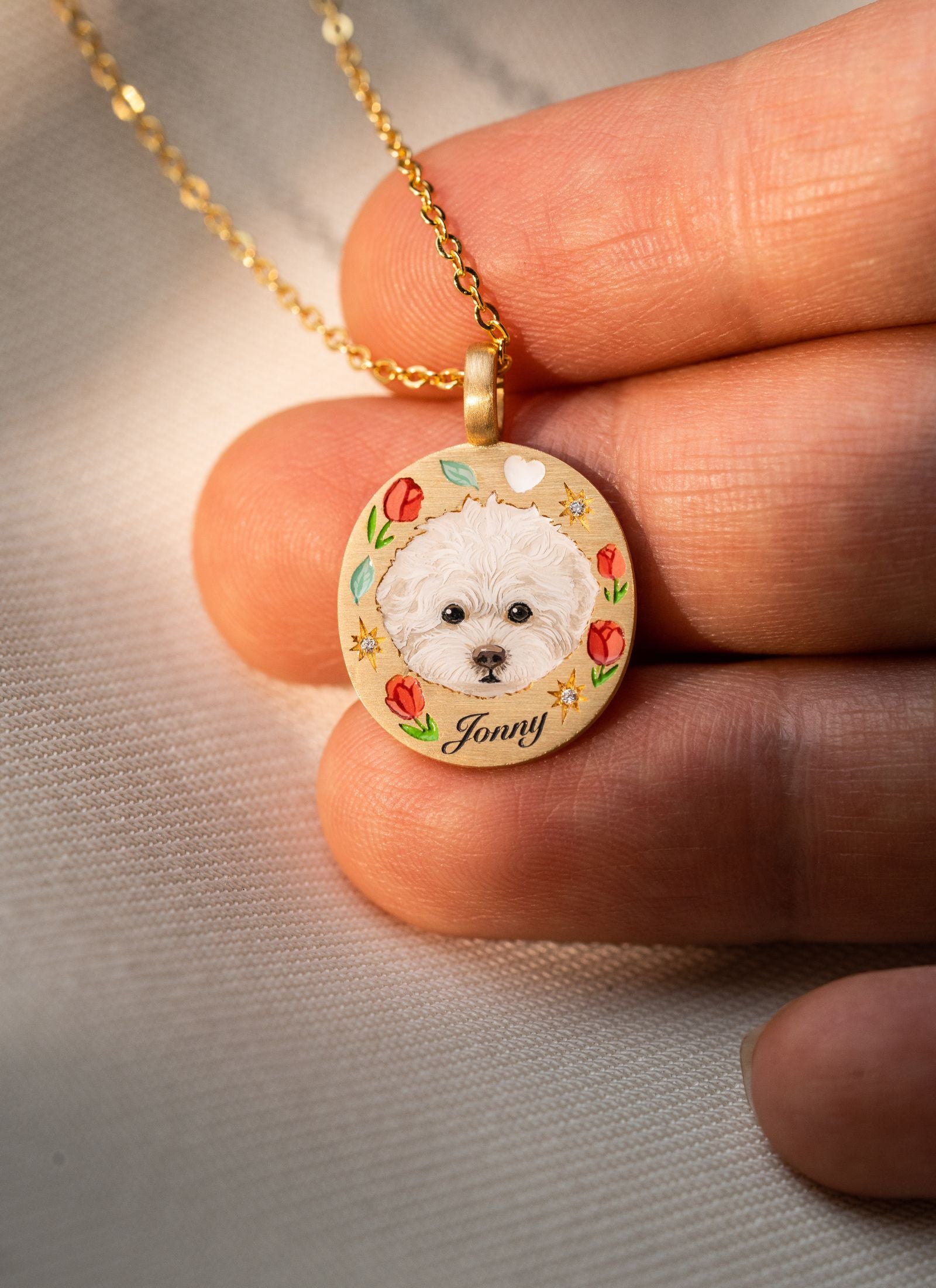 Close-up of a hand-painted dog portrait memorial necklace held in hand