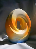 Load image into Gallery viewer, A modern pet urn with a cat silhouette carved into an abstract crescent moon design, featuring smooth curves and warm gradient colors of orange, gold, and blue.
