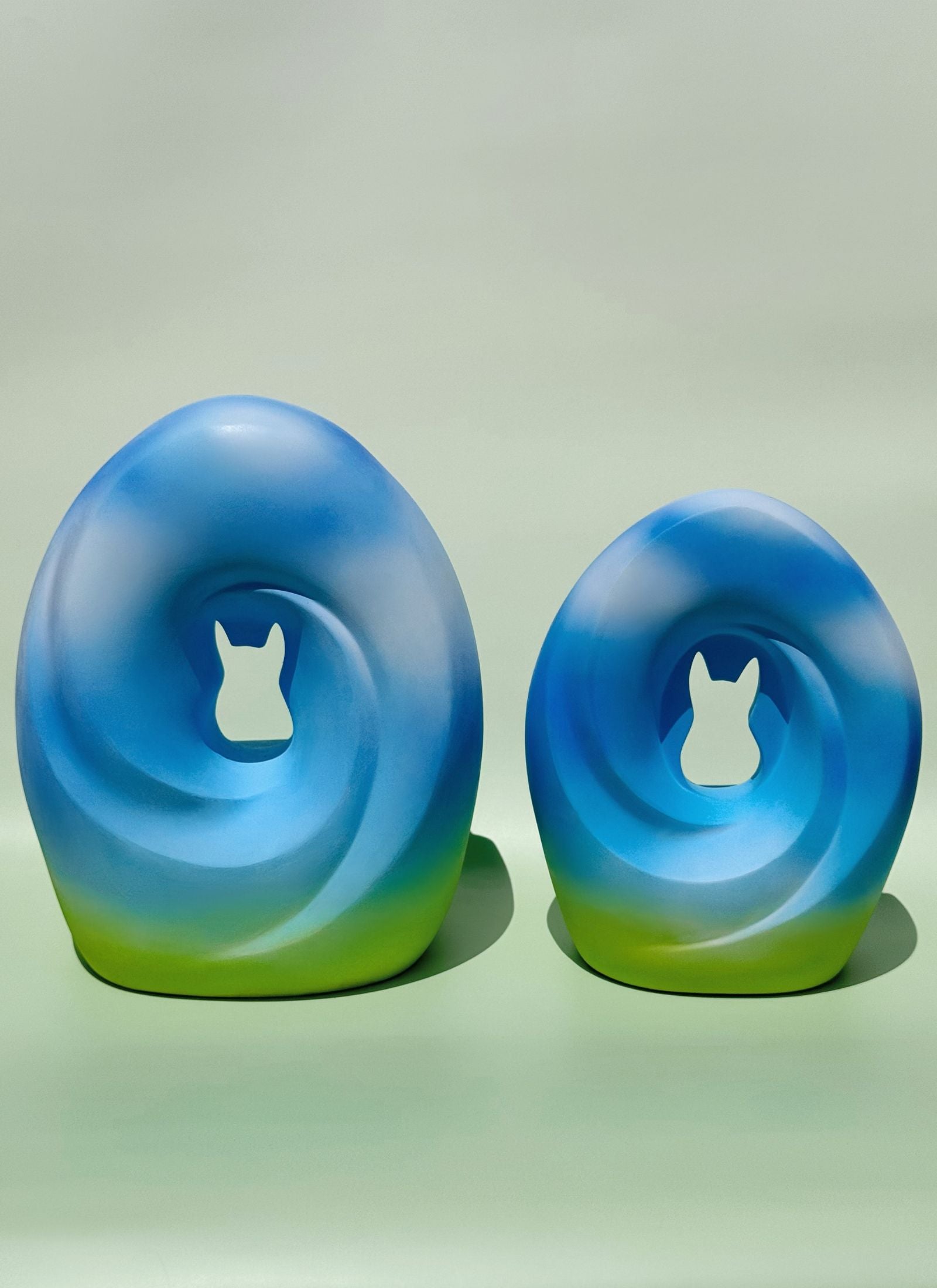 A pair of Meadow Song Pet Urns placed side by side, symbolizing peace and harmony with their soft blue and green hues.