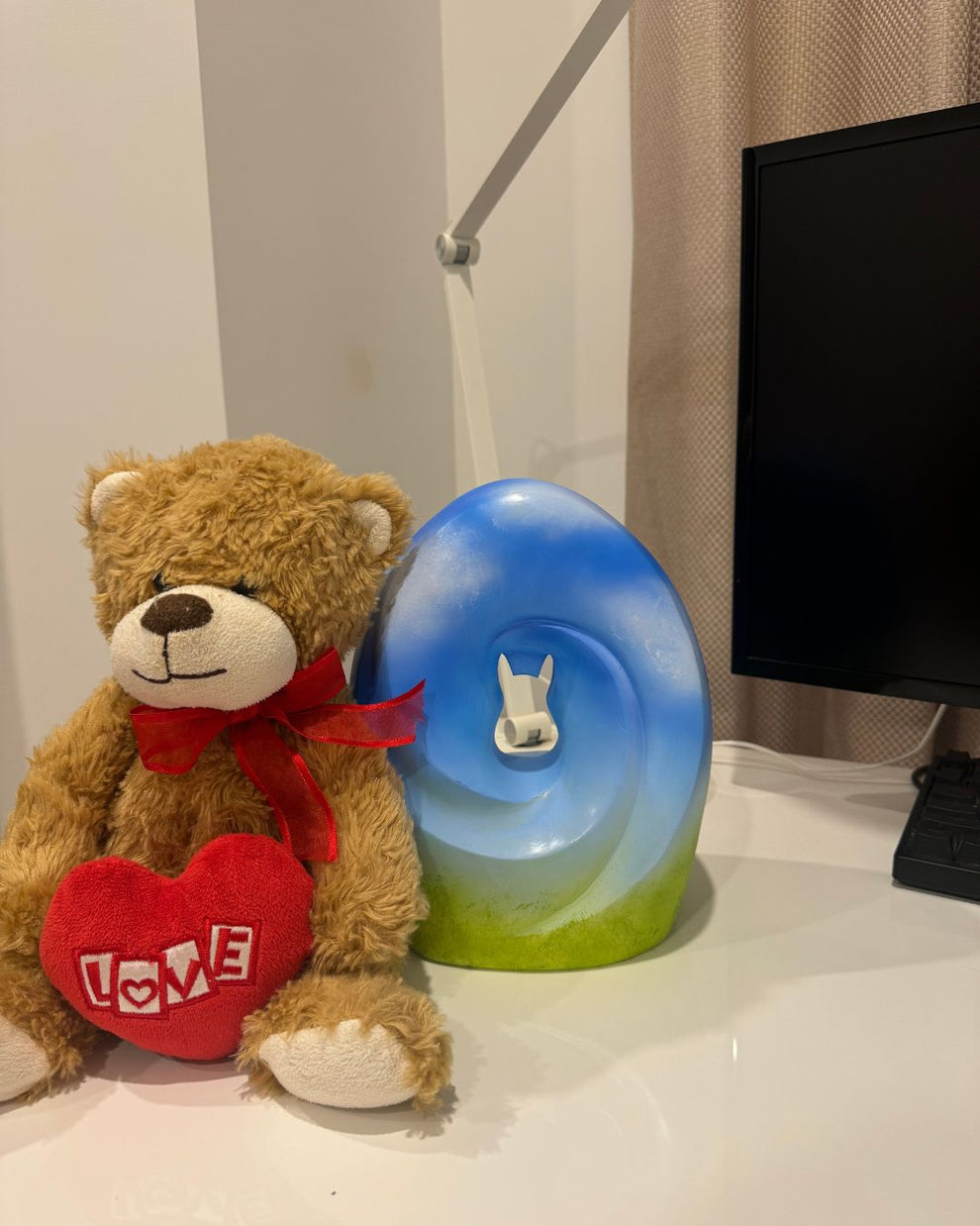 Missouly Meadow Song Pet Urn beside a teddy bear, accompanied by Alyssa's testimonial on how it helped her cope with the loss of her cat, bringing back happy memories.