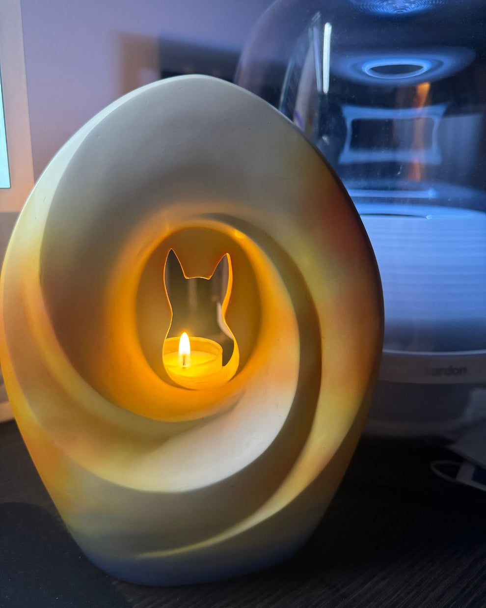 Missouly Sunset Memories Pet Urn with a candle lit inside, accompanied by a testimonial from Linda sharing how it brings her comfort and celebrates her pet Cooper’s life.