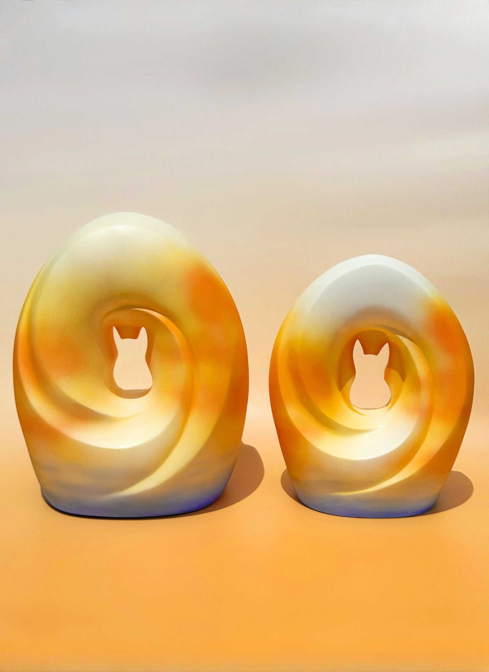 Two sizes of the Sunset Memories Pet Urn with soft, glowing tones representing the transition to a new chapter.